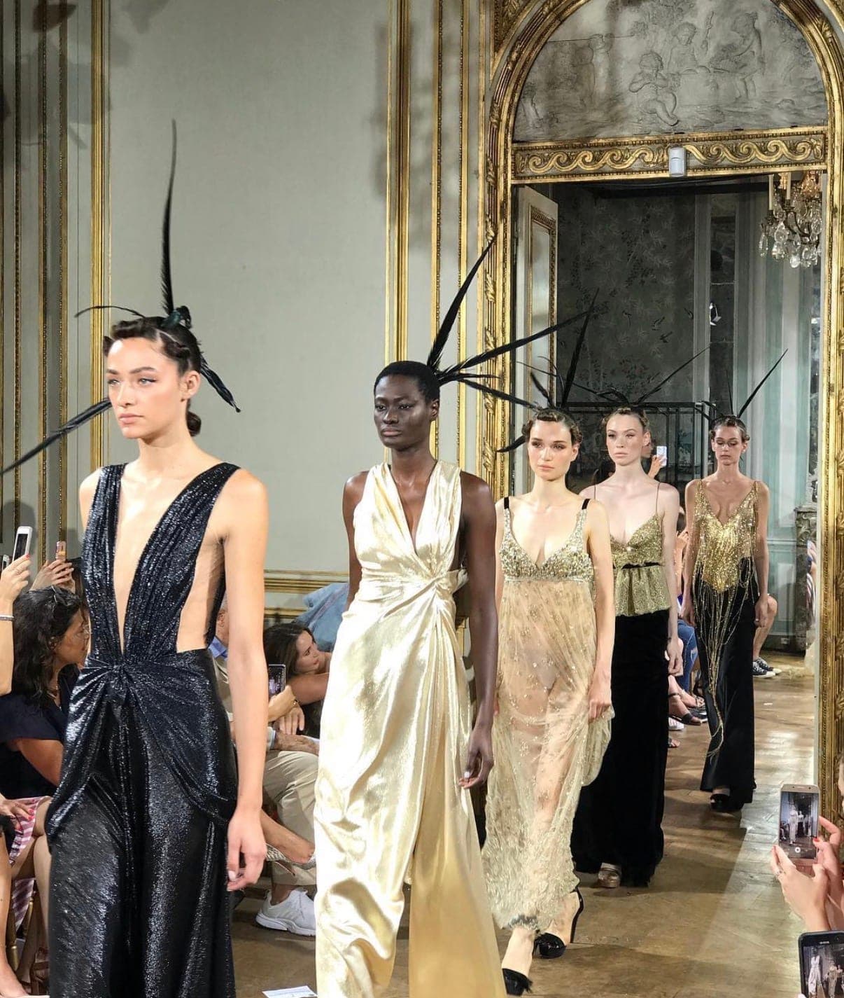 Models walking a couture show in gold gowns